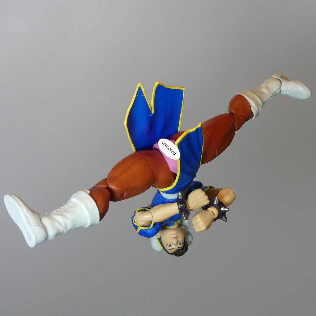 Street Fighter Chun-Li action figure posed upside down against a solid gray background.