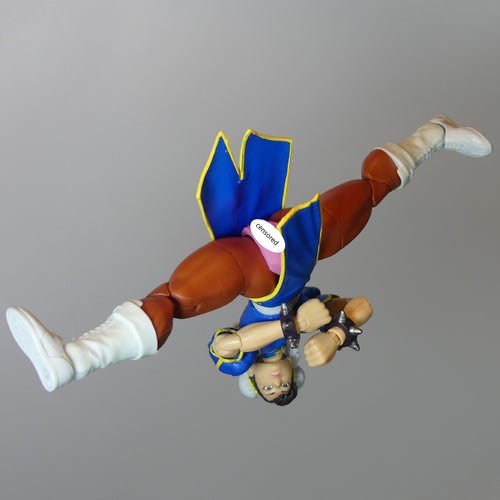 Street Fighter Chun-Li action figure posed upside down against a solid gray background.