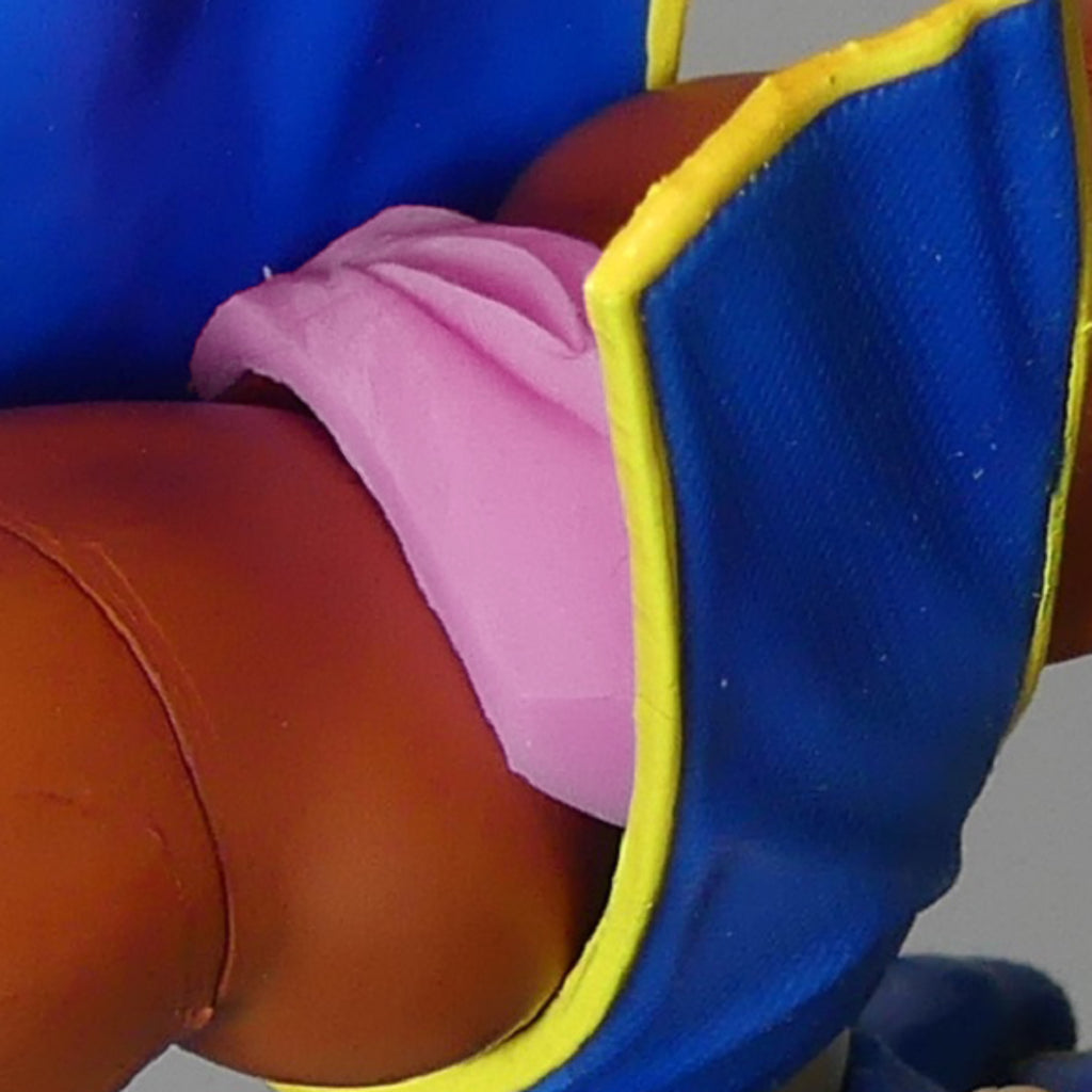 Chun li wearing a blue outfit with yellow trim and a pink silicone genitalia, shown against a plain light gray background.