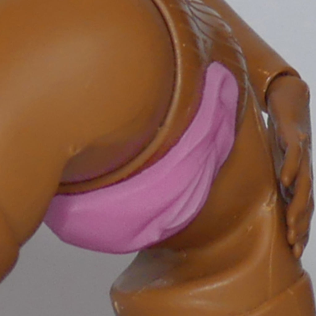 Close-up of a brown plastic doll torso wearing a pink silicone anus, against a plain light gray background.
