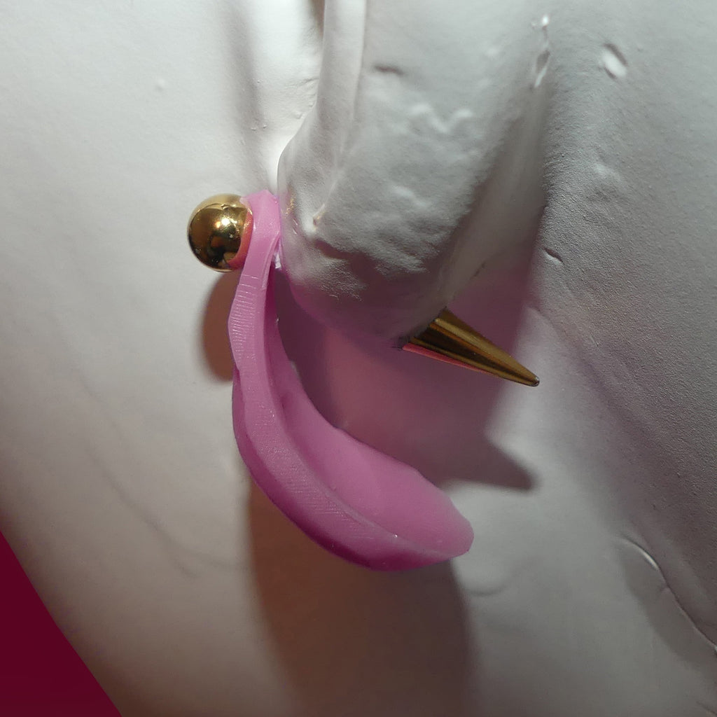 A close-up of a pink curved earring with a gold-tone ball and spike, shown on a white mannequin ear.