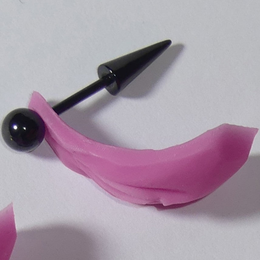 A black metal tongue piercing barbell with a pink silicone or rubber vulva vagina, shown on a plain light background.