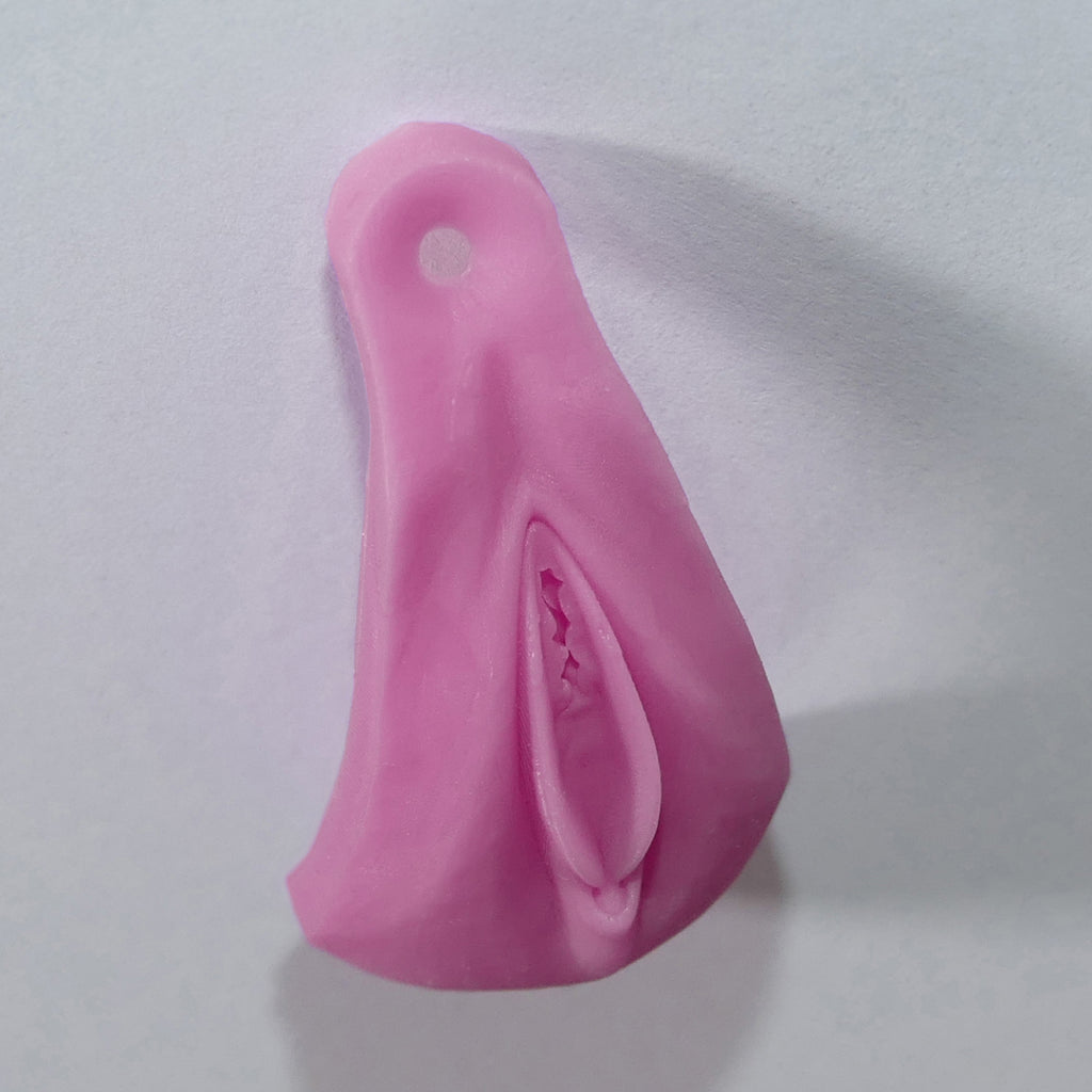 A pink silicone vulva novelty product with a textured, realistic anus, shown on a plain light gray background.